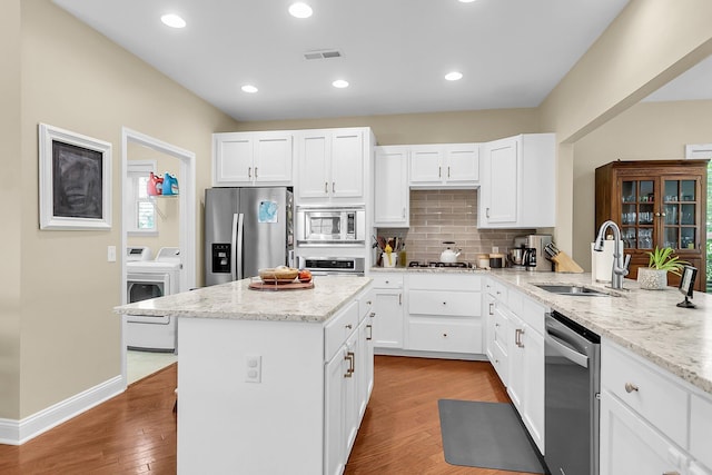 kitchen featuring visible vents, independent washer and dryer, a sink, appliances with stainless steel finishes, and backsplash