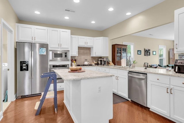 kitchen with stainless steel appliances, visible vents, wood finished floors, and a peninsula