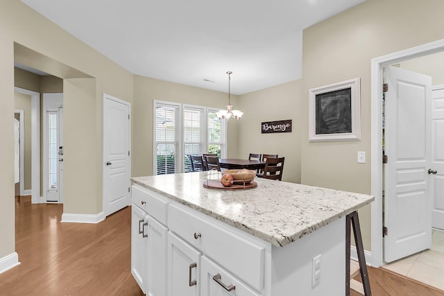 kitchen with light wood-style floors, hanging light fixtures, white cabinetry, and a chandelier