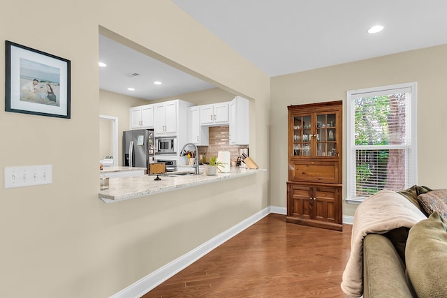 interior space with a peninsula, stainless steel appliances, dark wood-style flooring, and white cabinetry
