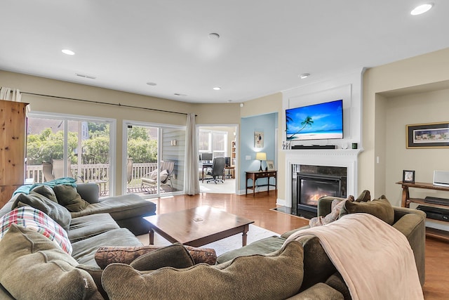 living area featuring recessed lighting, a fireplace with flush hearth, wood finished floors, and visible vents
