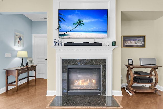details featuring baseboards, a fireplace with flush hearth, wood finished floors, and visible vents