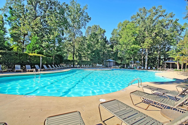 community pool with a patio, a gazebo, and fence