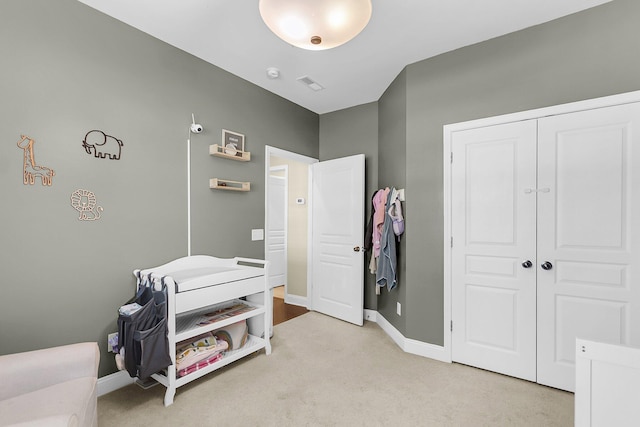 bedroom featuring baseboards, a closet, visible vents, and light carpet