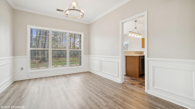 empty room with a notable chandelier, hardwood / wood-style flooring, and plenty of natural light