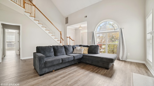 living room with wood-type flooring, a high ceiling, and plenty of natural light