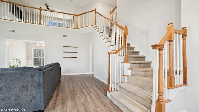 stairs with wood-type flooring and a high ceiling