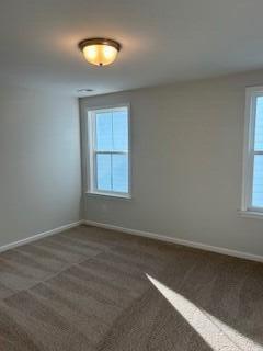 spare room featuring dark carpet and plenty of natural light