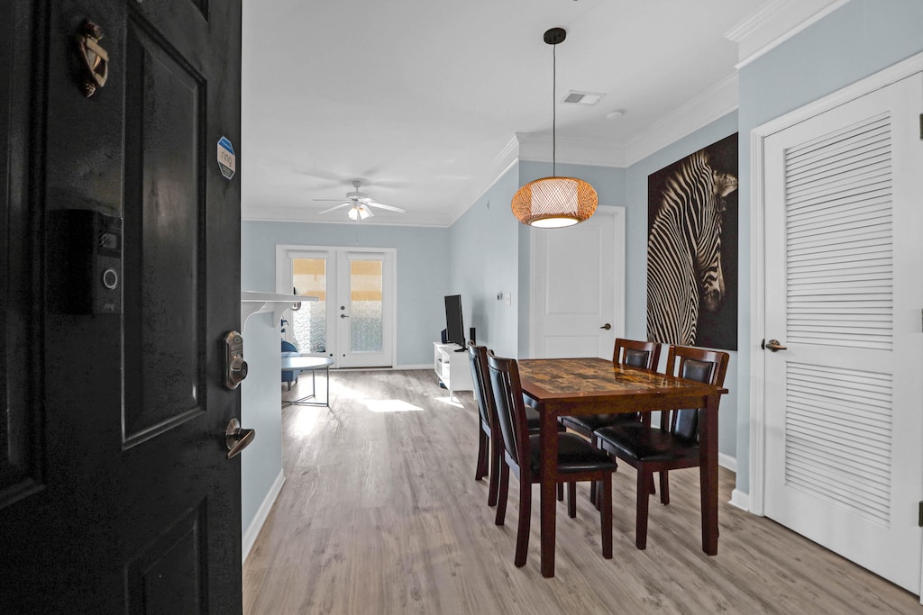 dining space with light hardwood / wood-style floors, ceiling fan, crown molding, and french doors