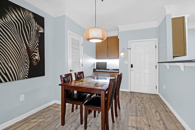 dining area with light wood-type flooring and ornamental molding