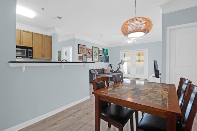 dining room with light hardwood / wood-style floors, ceiling fan, crown molding, and french doors