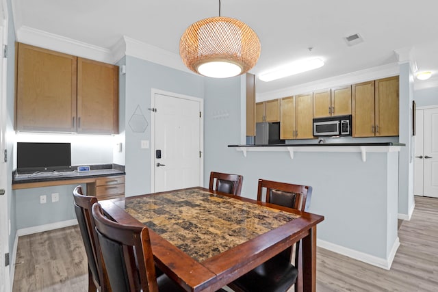 dining area with ornamental molding and light hardwood / wood-style flooring