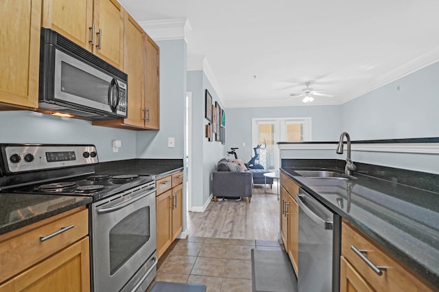 kitchen with light hardwood / wood-style floors, sink, appliances with stainless steel finishes, dark stone counters, and crown molding