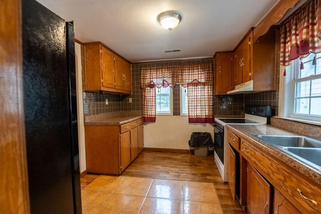 kitchen featuring white electric range oven, decorative backsplash, and a wealth of natural light