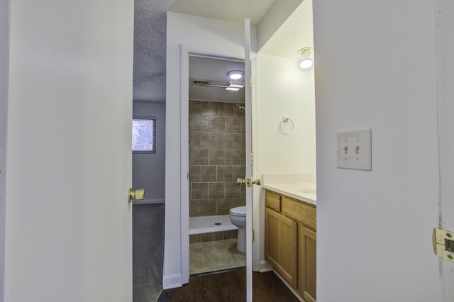 bathroom with toilet, vanity, wood finished floors, and a stall shower