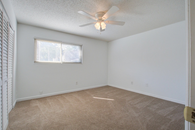 carpeted spare room with ceiling fan and a textured ceiling