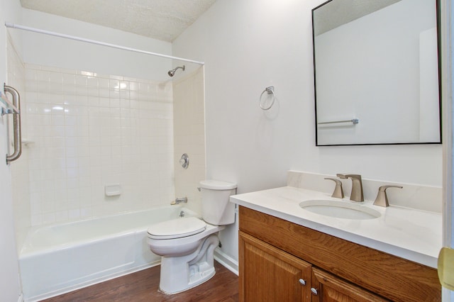 full bathroom featuring toilet, wood-type flooring, tiled shower / bath, vanity, and a textured ceiling