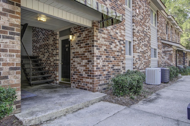 doorway to property with brick siding and central AC