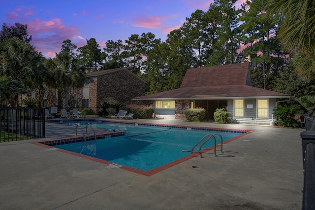 pool at dusk with a patio area