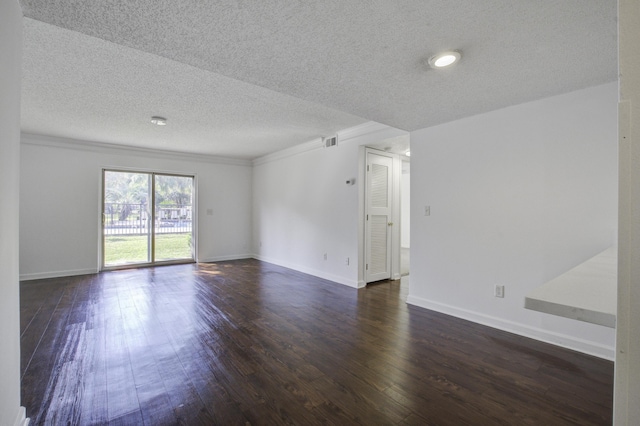 empty room with a textured ceiling, crown molding, dark wood-style floors, and visible vents