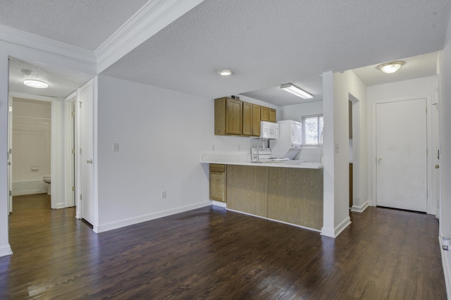 kitchen with brown cabinetry, dark wood-style flooring, a textured ceiling, and white microwave