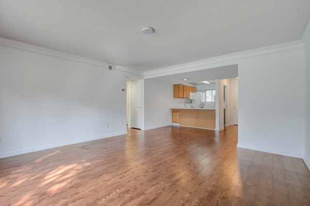 unfurnished living room featuring wood-type flooring, ornamental molding, and a textured ceiling