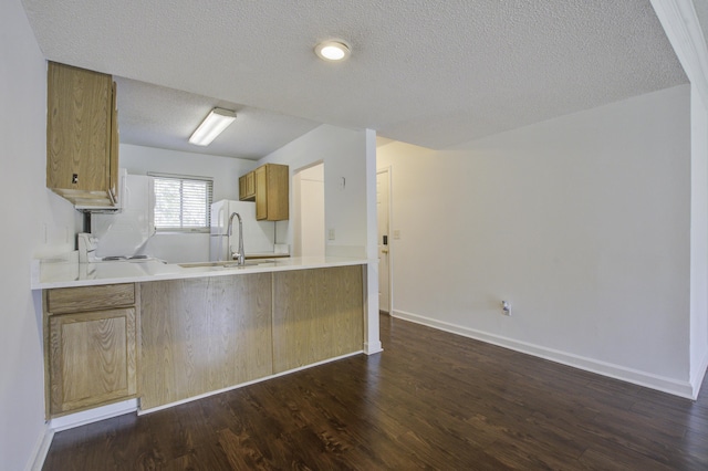 kitchen with stove, a sink, dark wood-type flooring, a peninsula, and a textured ceiling