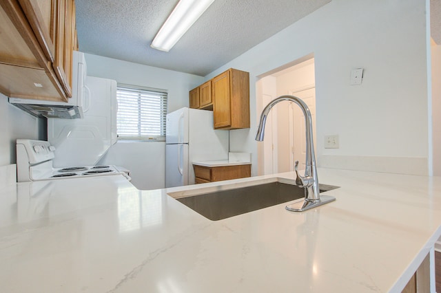 kitchen with white appliances, sink, kitchen peninsula, and a textured ceiling