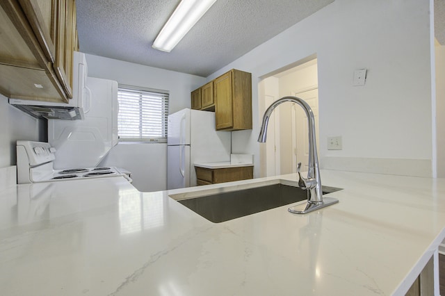 kitchen with white appliances, a sink, brown cabinets, and light stone counters