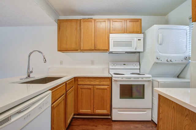 kitchen with stacked washer / drying machine, sink, white appliances, a textured ceiling, and dark hardwood / wood-style flooring