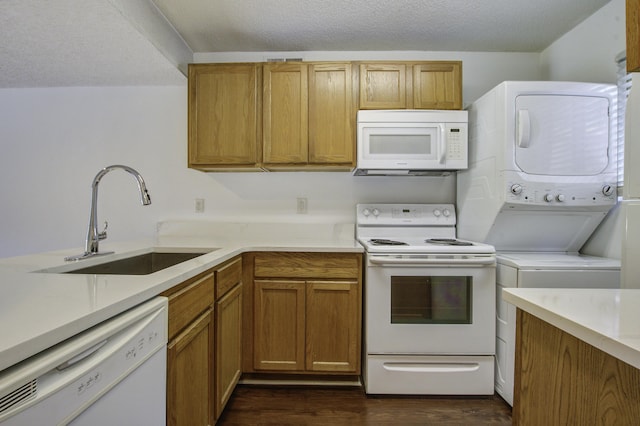 kitchen featuring a sink, dark wood-style flooring, white appliances, stacked washer / drying machine, and light countertops