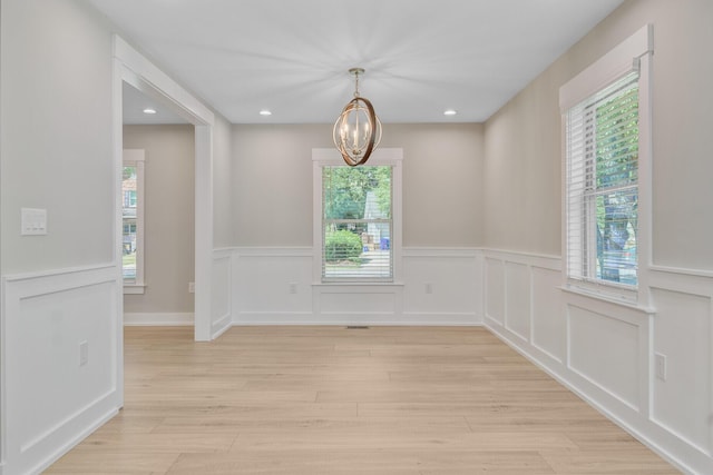 empty room with a chandelier, wainscoting, light wood-style flooring, and recessed lighting
