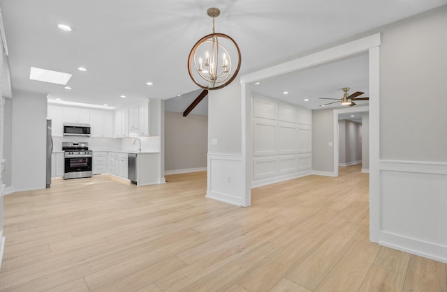 unfurnished living room featuring light wood-style floors, a chandelier, a ceiling fan, a sink, and recessed lighting