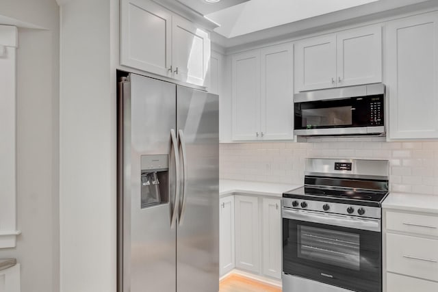 kitchen with stainless steel appliances, light countertops, decorative backsplash, and white cabinets