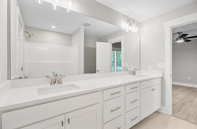 bathroom with a ceiling fan, double vanity, a shower, and baseboards