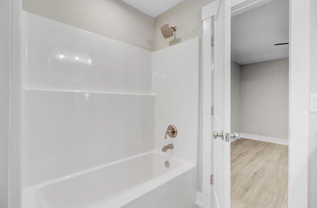 bathroom with baseboards, shower / tub combination, and wood finished floors