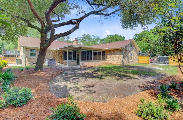 view of front of home featuring a chimney, a sunroom, fence, and brick siding