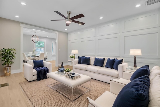 living area featuring ceiling fan, recessed lighting, baseboards, light wood finished floors, and a chandelier