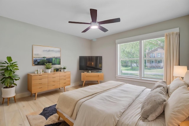 bedroom with light wood-type flooring, baseboards, and ceiling fan