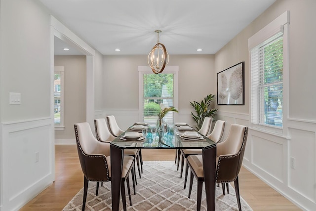 dining space with a chandelier, a decorative wall, light wood finished floors, wainscoting, and recessed lighting