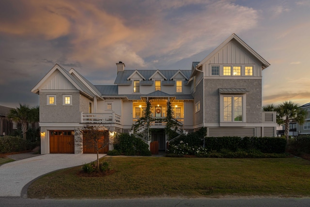 view of front of home featuring a garage, driveway, a standing seam roof, a yard, and board and batten siding