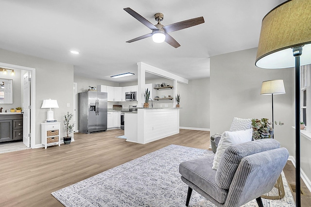 living room featuring light hardwood / wood-style floors, ceiling fan, and sink