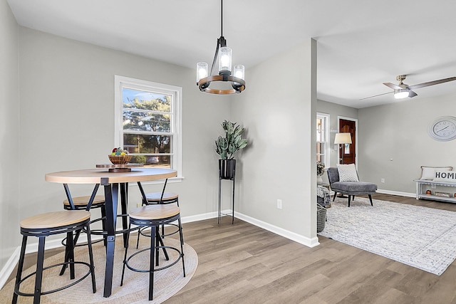 dining room featuring ceiling fan with notable chandelier and hardwood / wood-style flooring