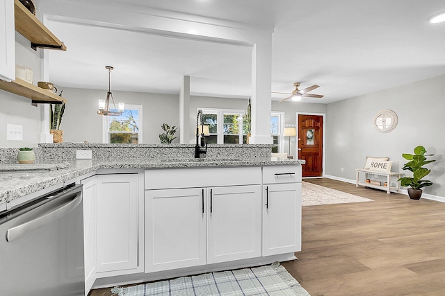 kitchen with light stone countertops, sink, white cabinets, and stainless steel dishwasher