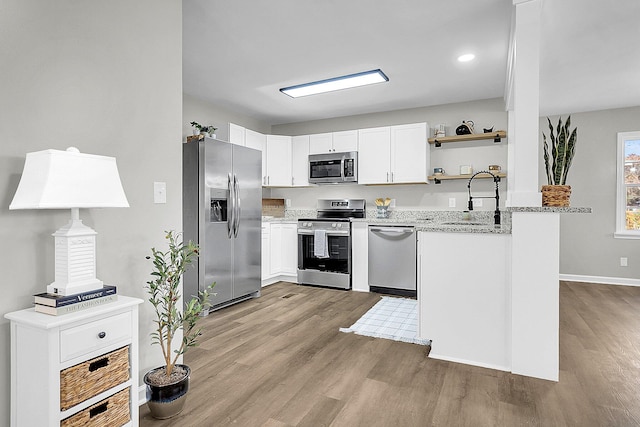 kitchen with white cabinetry, sink, stainless steel appliances, light stone counters, and light hardwood / wood-style floors