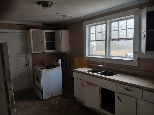 kitchen with white gas range, sink, white cabinets, and refrigerator