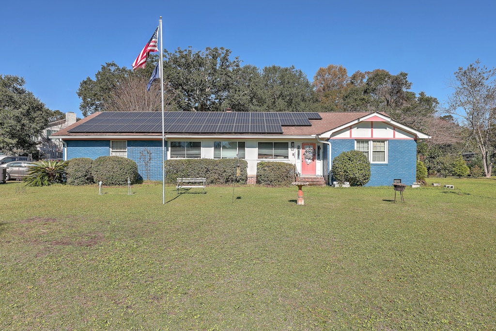 single story home with solar panels and a front yard