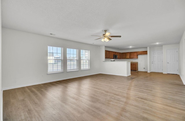 unfurnished living room featuring a textured ceiling, ceiling fan, and light wood-type flooring