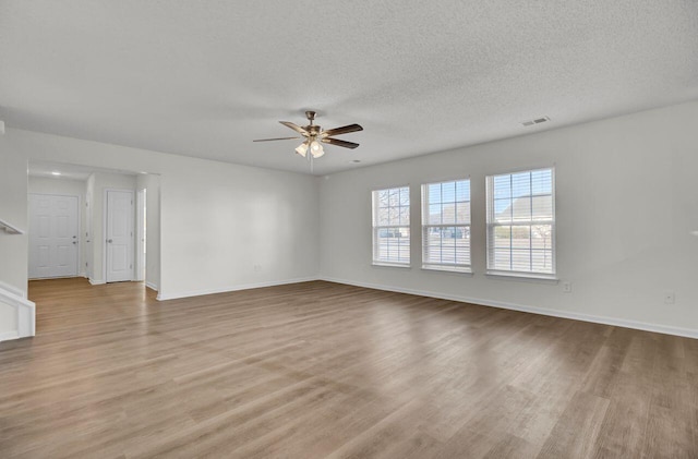 spare room with ceiling fan, a textured ceiling, and light wood-type flooring