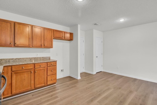 kitchen with light stone countertops, a textured ceiling, and light hardwood / wood-style flooring